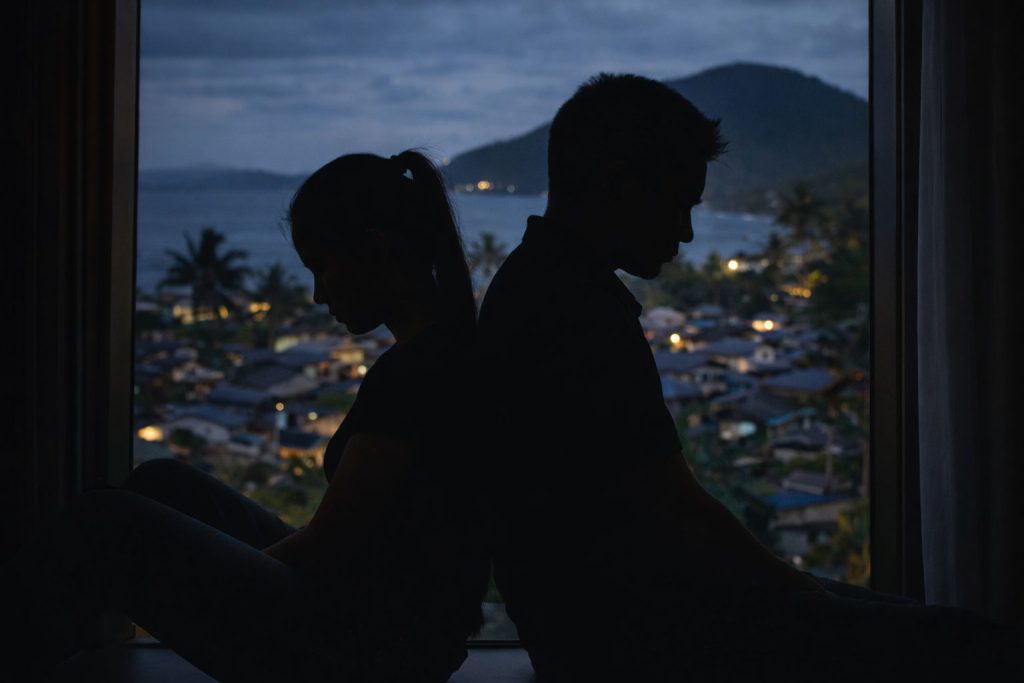 Silhouette of a Filipino couple sitting back to back, showing emotional distance and signs you haven’t moved on from your first love.