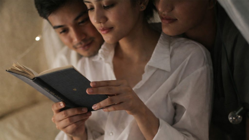A Filipino couple exploring modern relationship dynamics while reading together, reflecting open relationships explained in today’s context