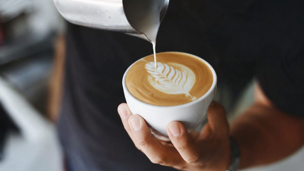 Close-up of a freshly made latte being prepared in a cozy café setting