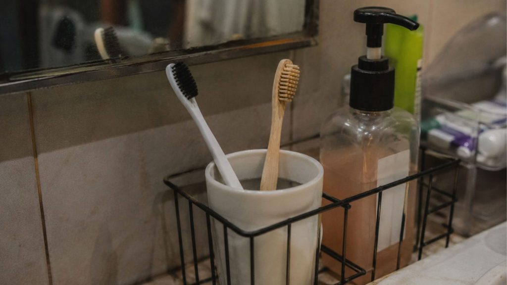 Toothbrushes stored beside a bathroom sink in a humid environment