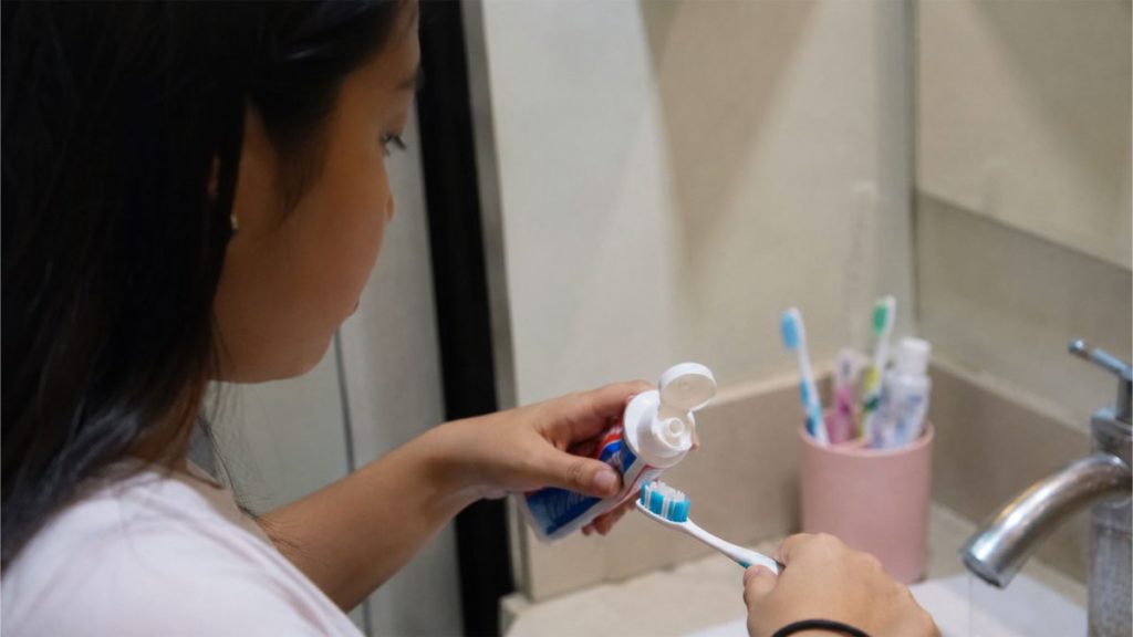 Filipino woman preparing a toothbrush with toothpaste in a bathroom