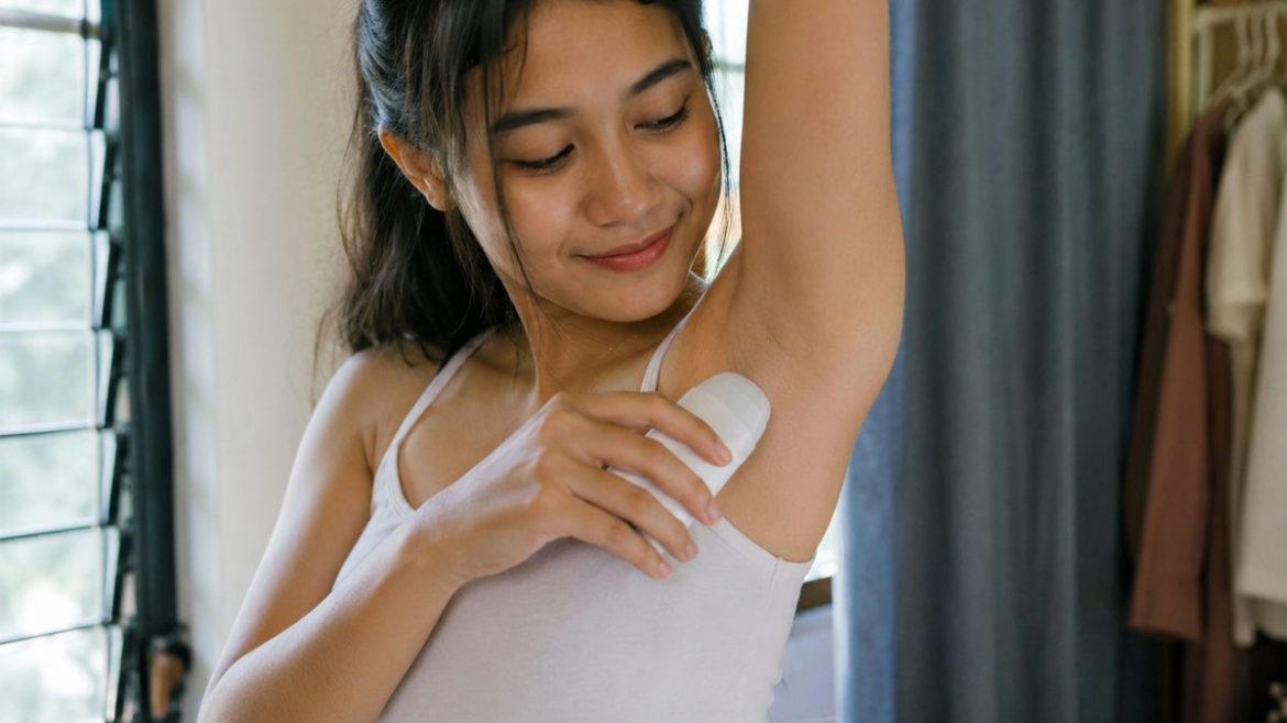 Young Filipina woman applying deodorant as part of her daily underarm hygiene routine
