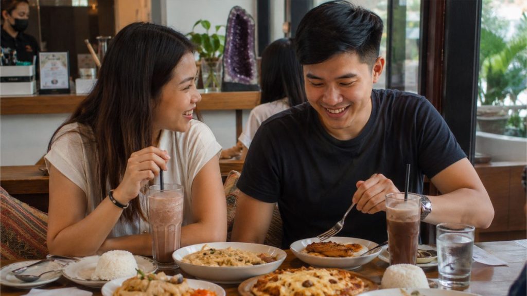 Young Filipino couple smiling while eating together at a cozy restaurant