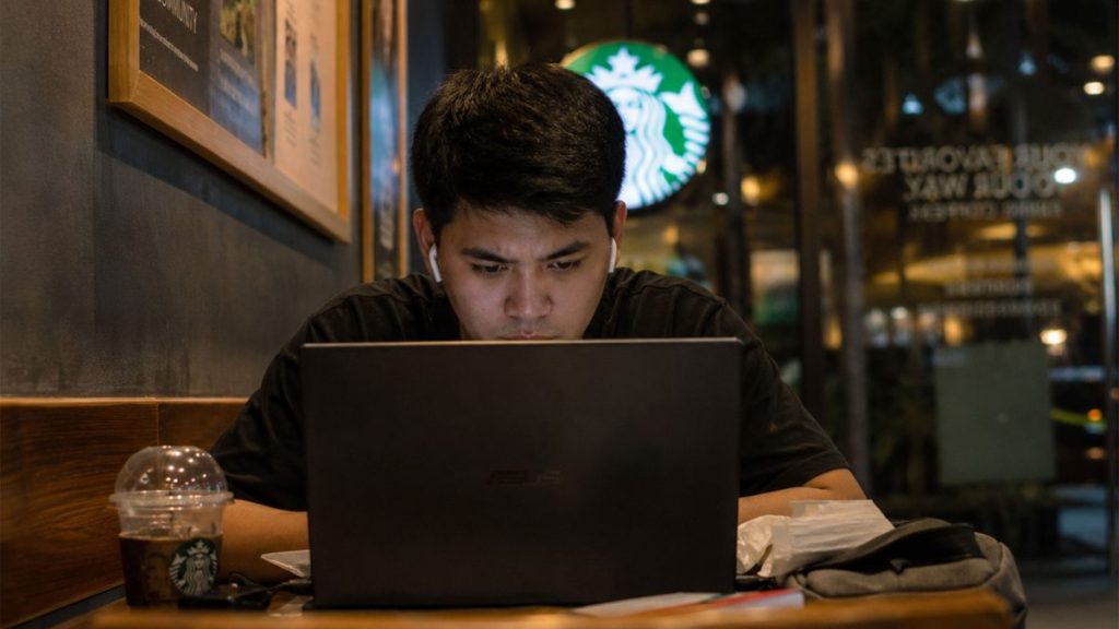 Filipino man working late on a laptop inside a café at night