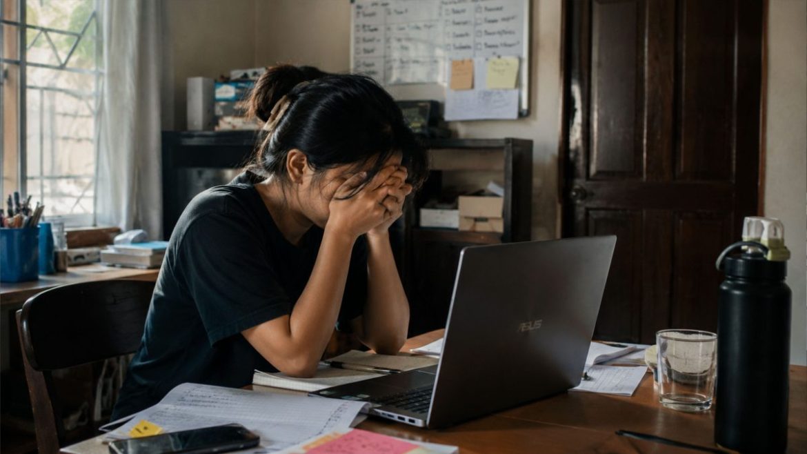 Filipino woman feeling stressed and emotionally exhausted while working on a laptop at home
