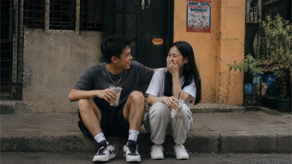 Filipino couple sitting on a quiet street while sharing a funny moment