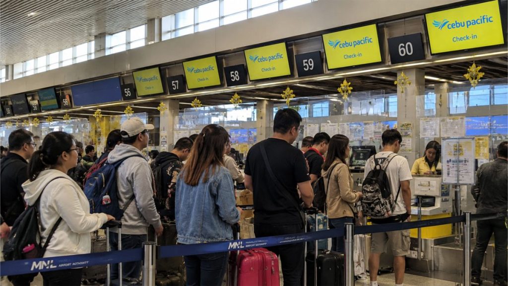 Filipino travelers with luggage carts preparing for airport check-in.