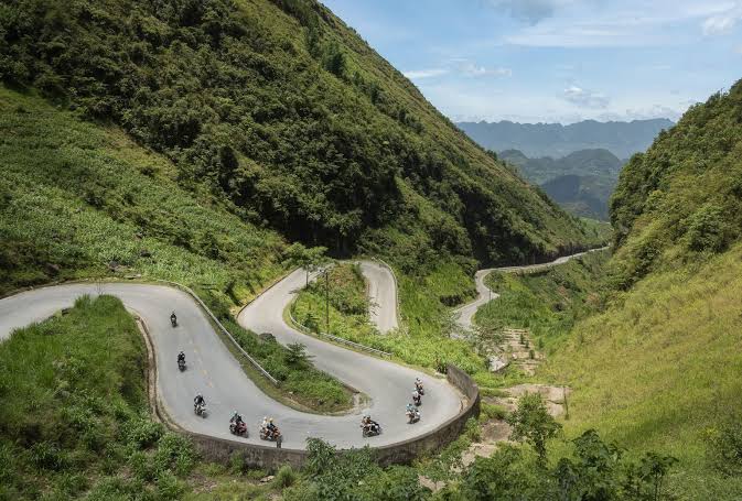 Winding mountain road cutting through the rugged valleys of Ha Giang in Northern Vietnam.