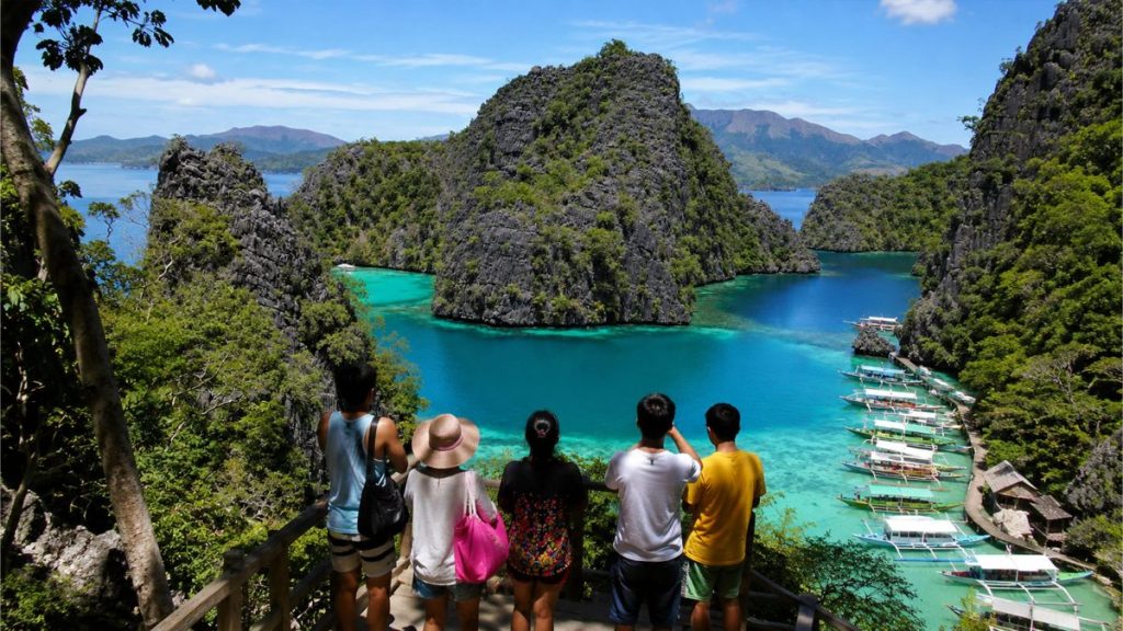 Filipino travelers overlooking Palawan's turquoise lagoons and limestone cliffs