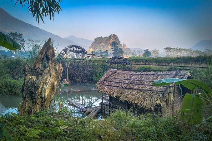 Traditional bamboo water wheels and lush green countryside scenery in Pu Luong Nature Reserve, Vietnam.
