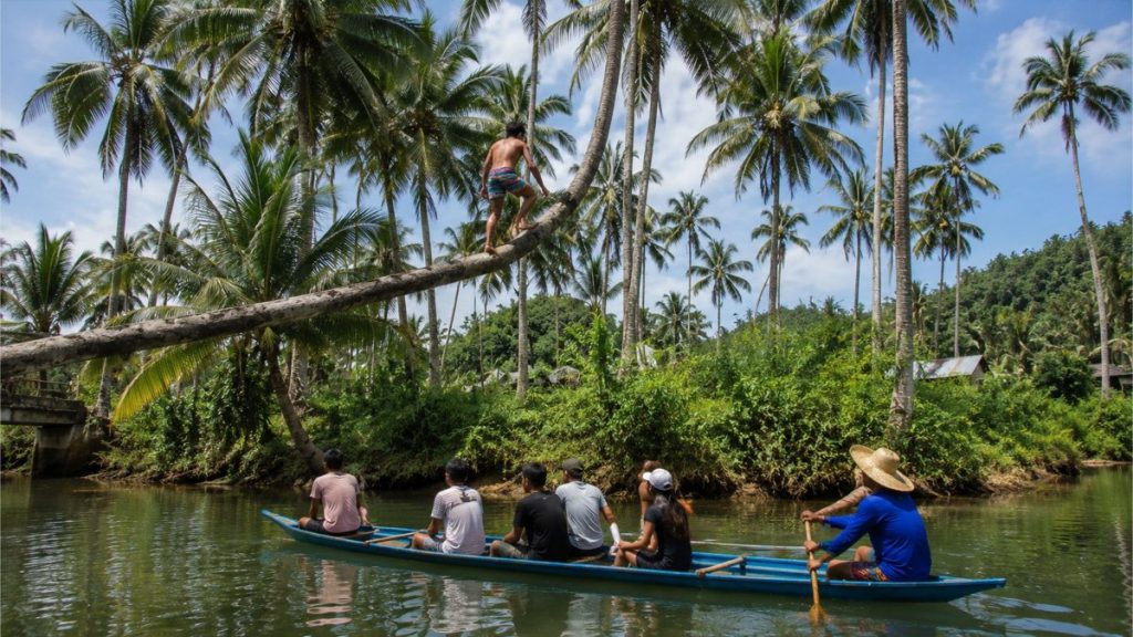 Travelers riding a boat through a scenic river lined with coconut trees in Siargao